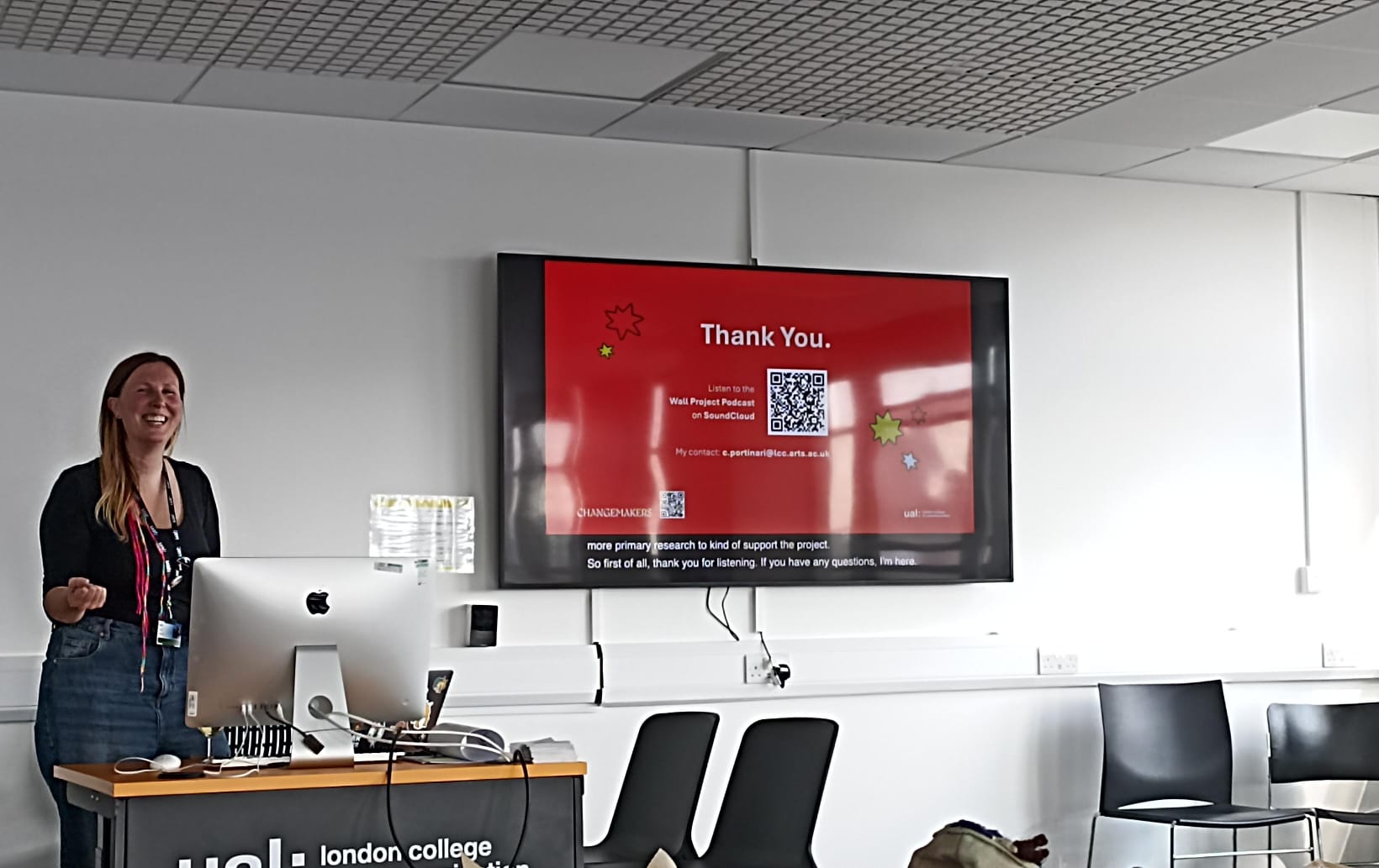 Chiara presenting near a screen. They are smiling. On the screen a 'Thank you' slide.