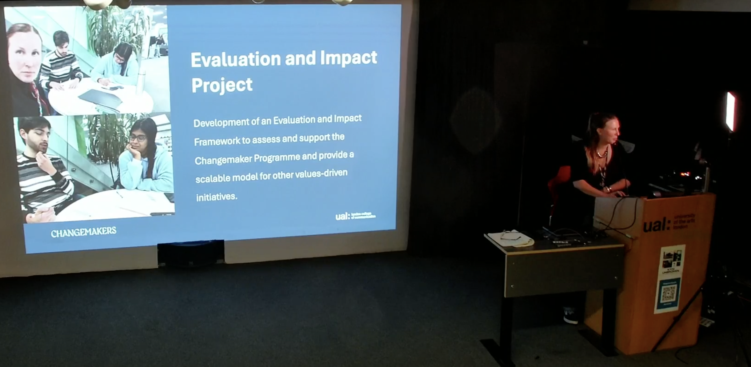 Chiara presenting on a stage with a screen presenting a slide titled Evaluation and Impact Project